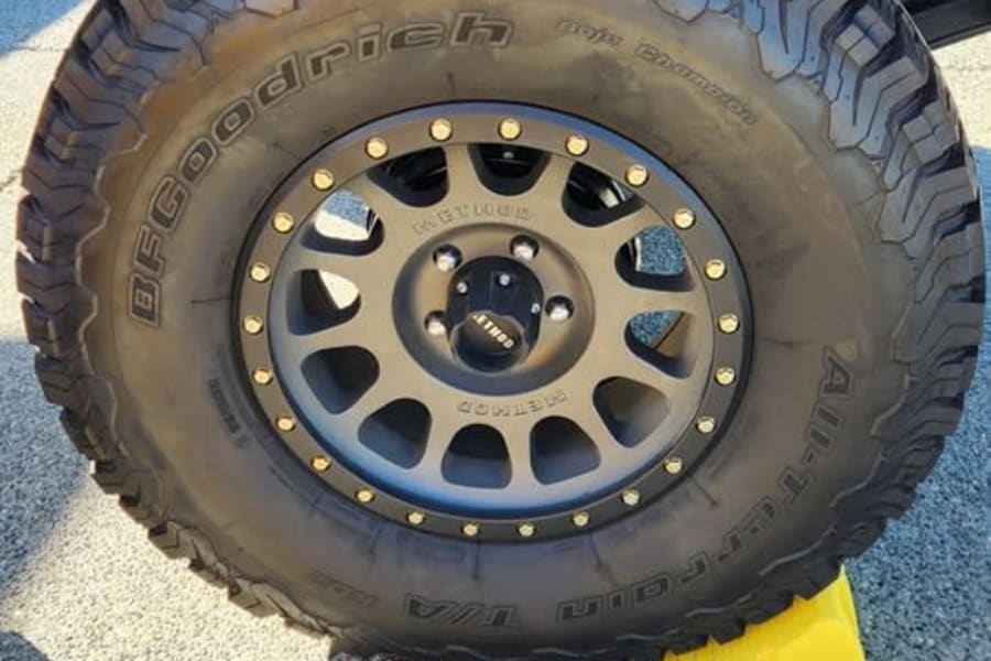 Rugged BFGoodrich tire & Method wheel on an RV rental, secured by a yellow leveler. Ready for adventure!
