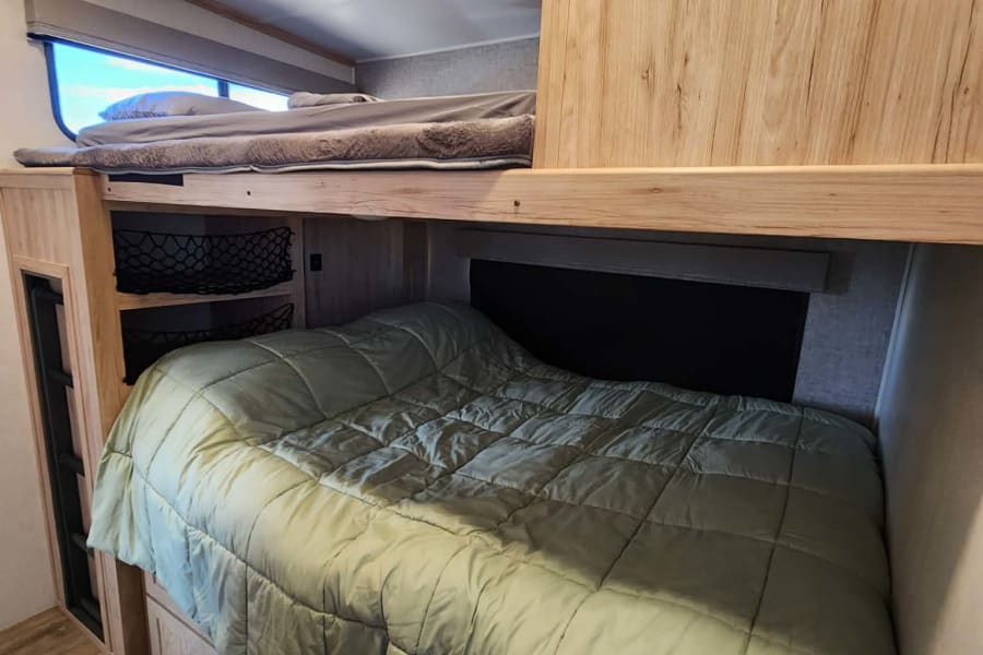 Cozy rv rental bunk beds with storage nets, drawers, and a window for natural light. Perfect sleeping area!