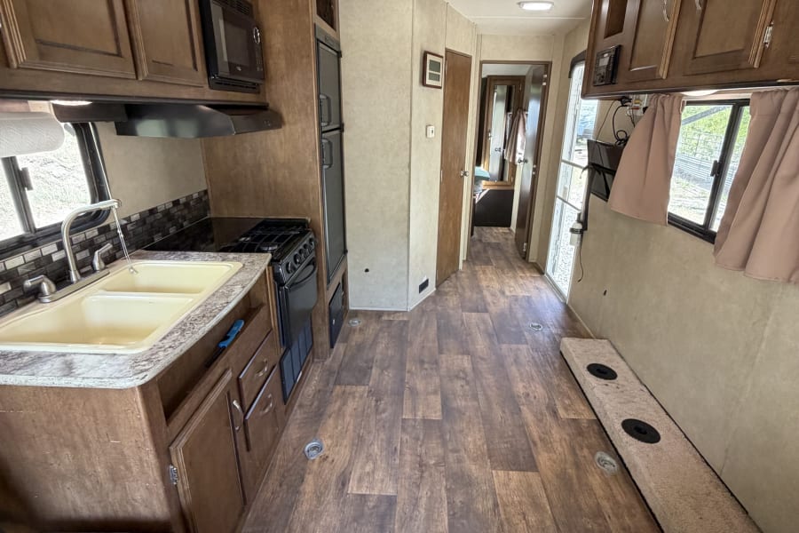 Spacious rv rental interior with a full kitchen, living area, and durable wood-look flooring, ready for your next adventure.