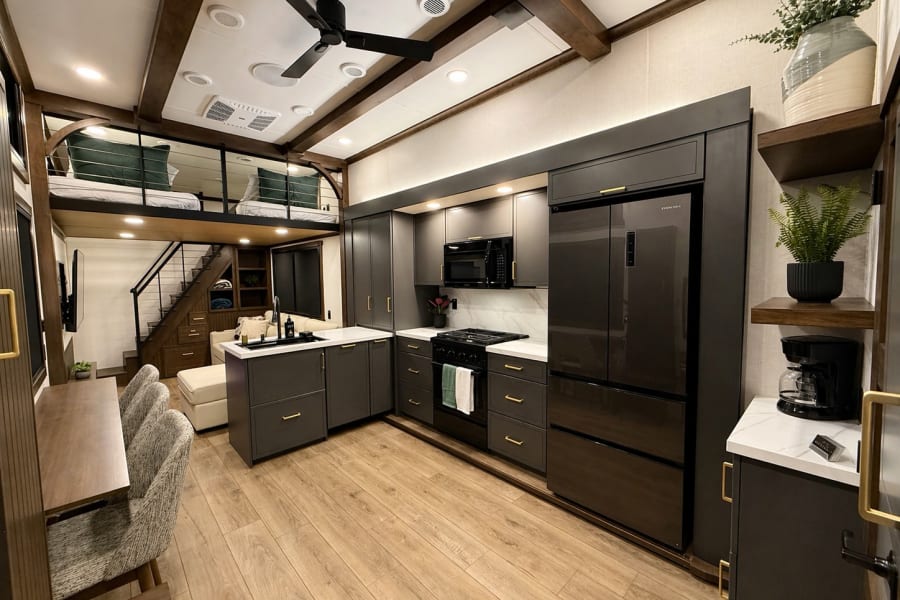 Modern RV rental interior: kitchen, loft beds, and dining area in a stylish tiny home design.