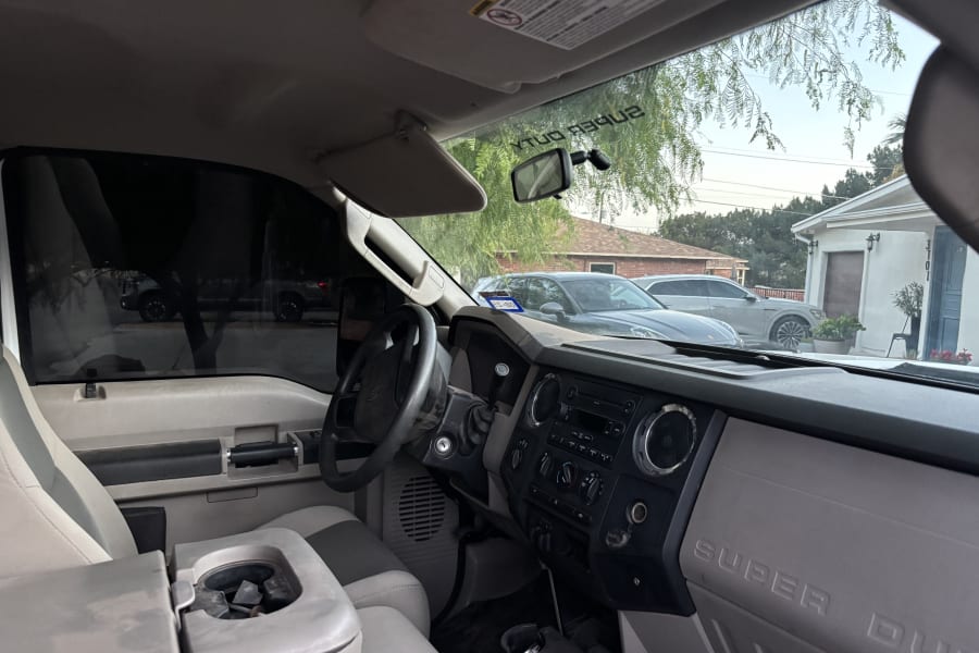 View from inside a Ford Super Duty truck's cab, showing dashboard & steering wheel. Residential street outside. For your RV rental adventure.