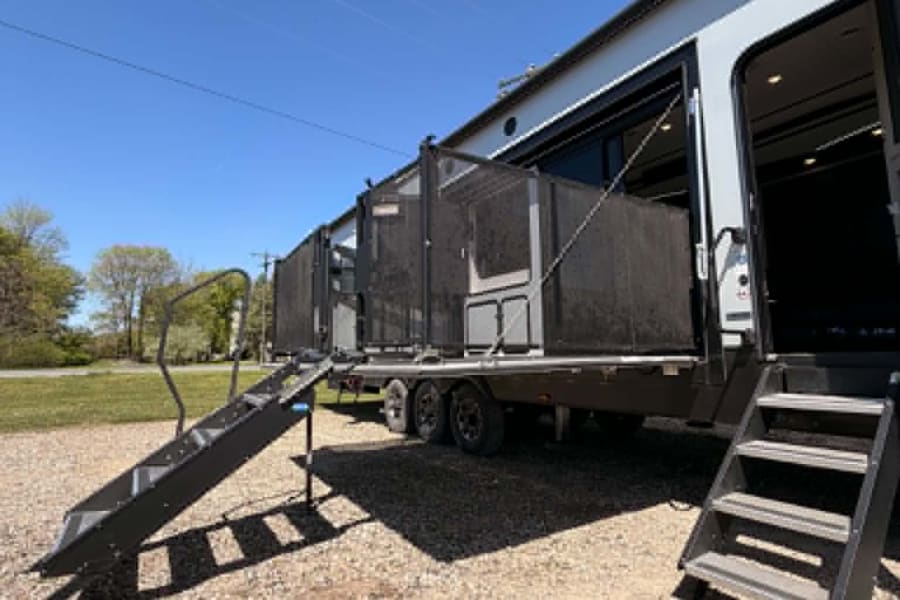 Spacious RV rental toy hauler with an extended outdoor patio and steps, ready for your adventure.