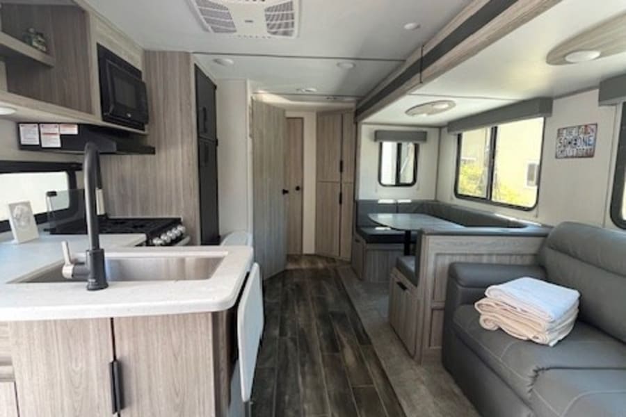 Spacious & modern RV rental interior featuring a kitchen, dinette, and sofa. Ready for your next adventure!