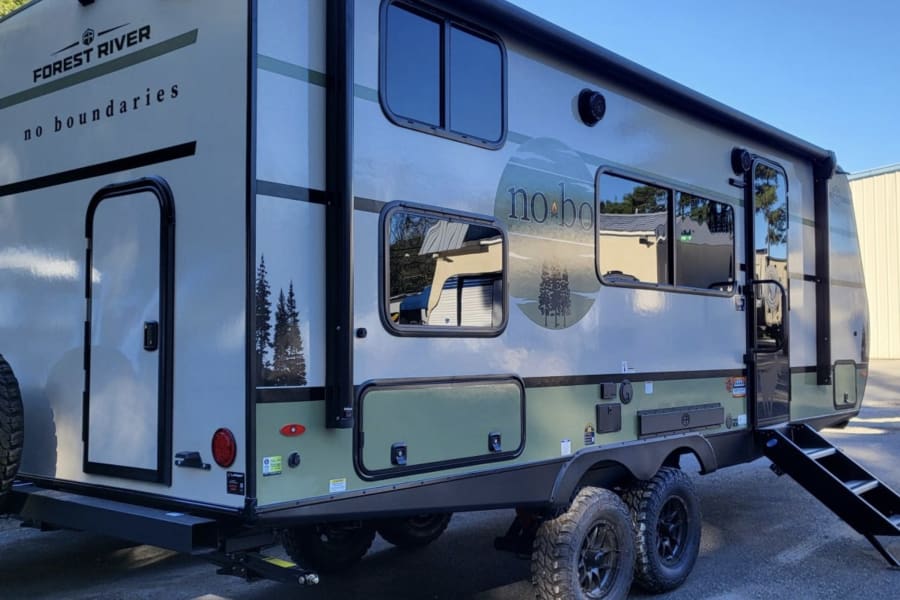 Explore with this Forest River No Boundaries travel trailer RV rental, showcasing off-road tires and outdoor entry steps.