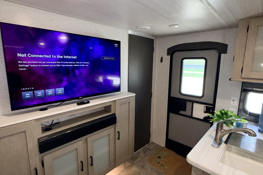 Modern RV rental interior with a large TV (showing 'Not Connected to Internet'), kitchen sink, and functional living space.