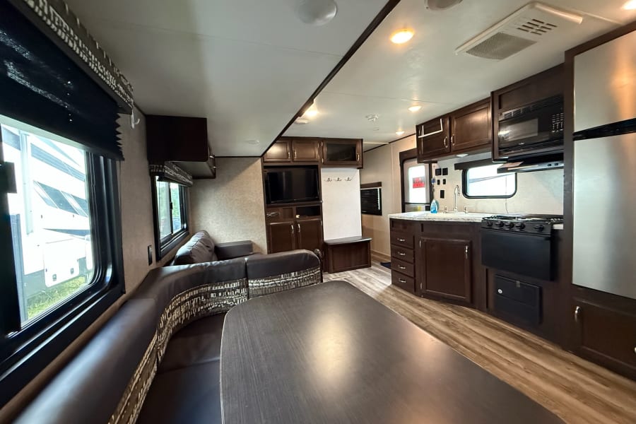 Spacious RV rental interior featuring a comfortable U-shaped dinette, full kitchen, and living area with ample natural light.
