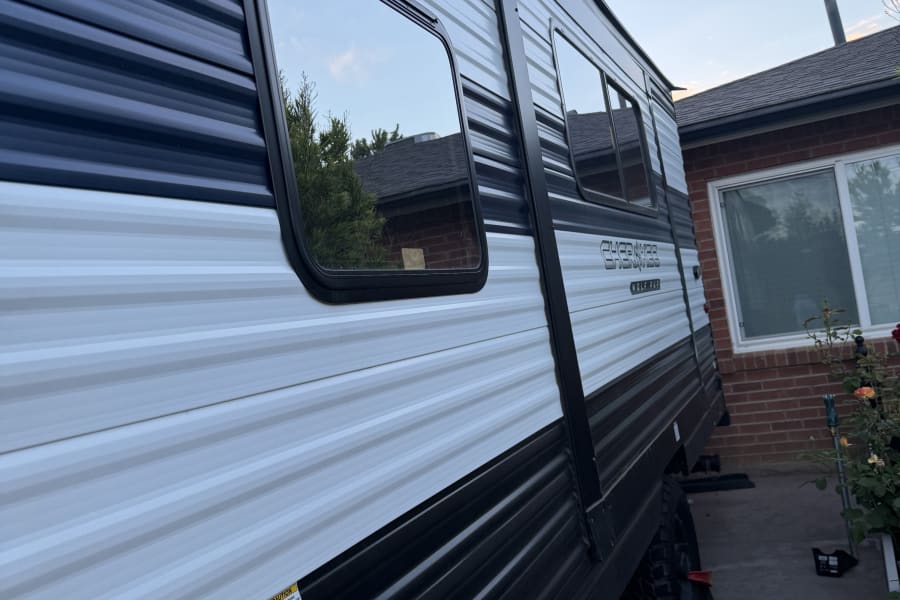 The side of a "Cherokee Wolf Pup" rv rental, showcasing reflective windows, fresh and city water connections, ready for travel.