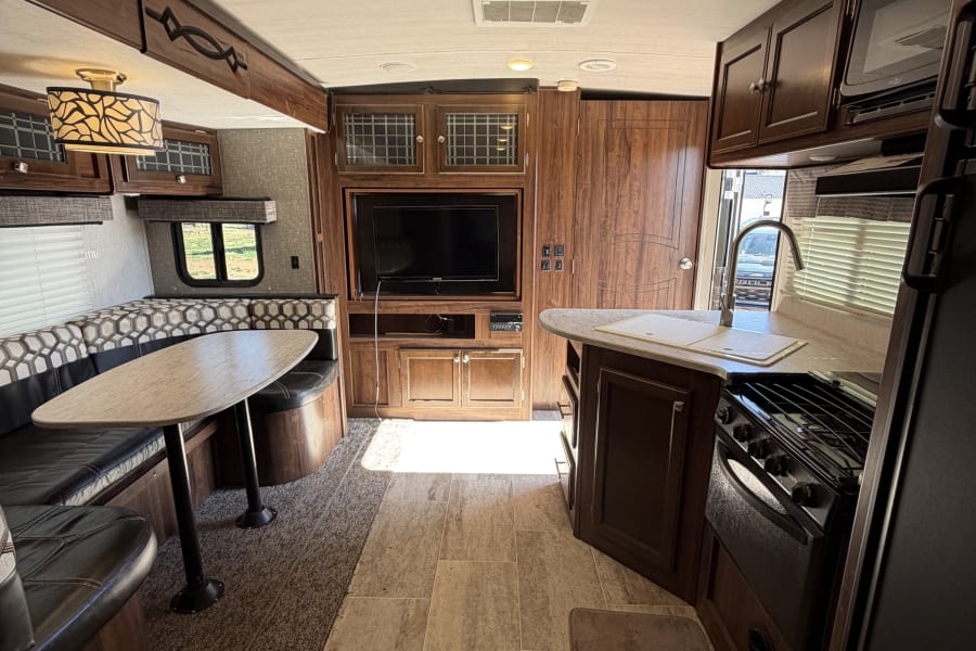 RV rental interior: A living area with dinette, entertainment center, and a compact kitchen.