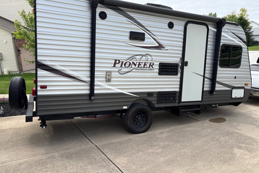 Pioneer Trail Blazer RV rental: side view of this travel trailer, showing its exterior, awning, entry door, and rear spare tire.