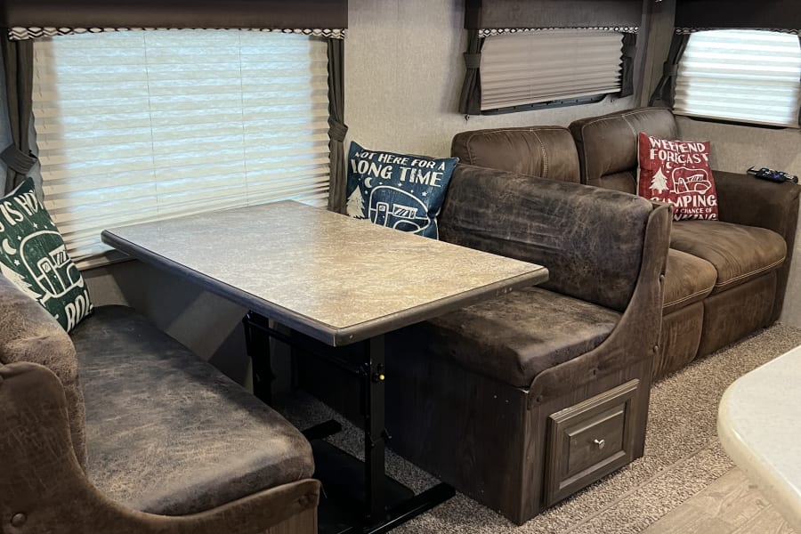 Step inside this inviting RV rental: a comfy dinette, sofa, and overhead storage for your next road trip adventure.
