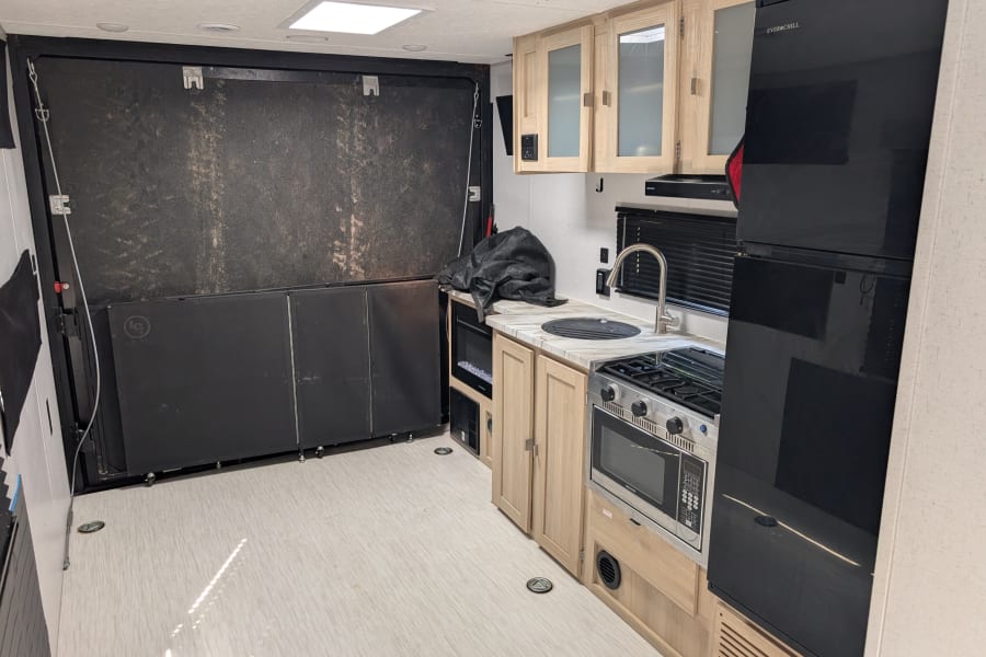 Spacious rv rental interior featuring a full kitchen with light wood cabinets, Everchill fridge, stove, sink, and versatile rear cargo area.