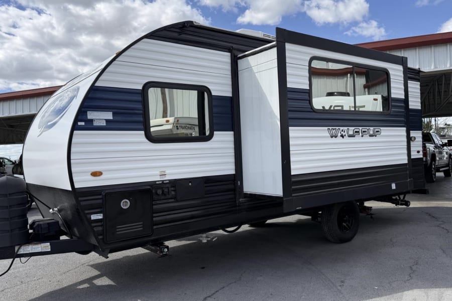 This black and white Wolf Pup travel trailer, with its slide-out extended, is ready for your next RV rental adventure.