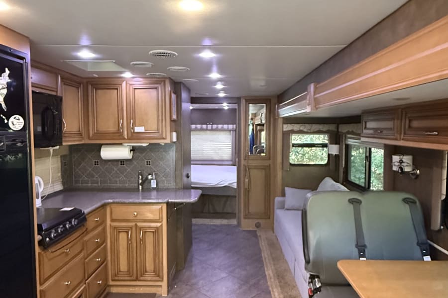 Inside an rv rental, featuring a fully equipped kitchen, comfortable dinette seating, and carpeted living space for journeys.