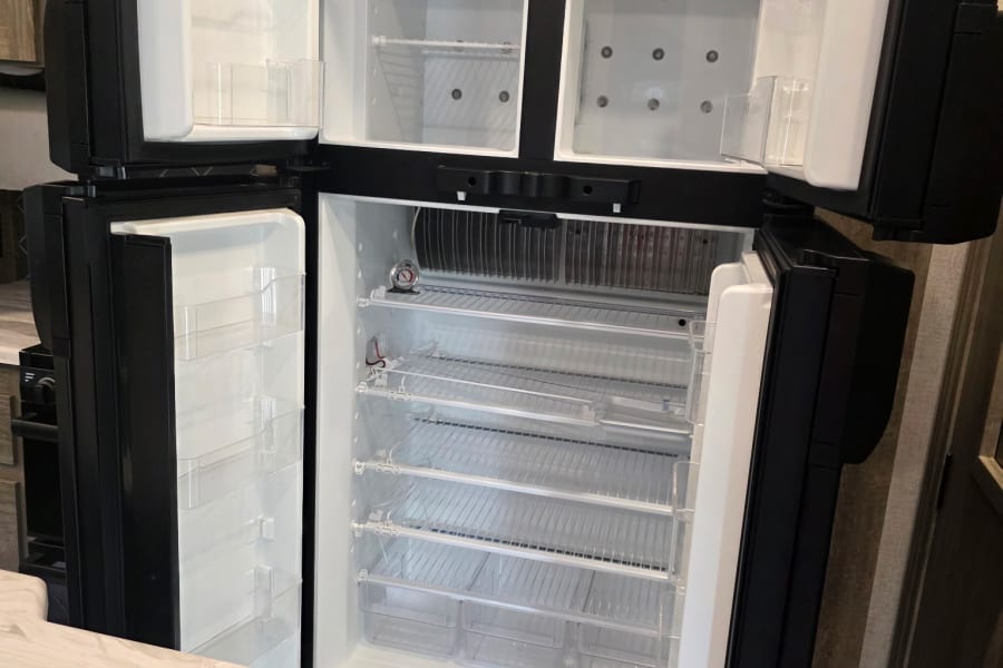 Spacious, clean Dometic RV refrigerator with open doors, featuring empty shelves and freezer compartments, perfect for an rv rental.