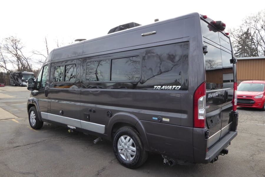 Dark gray Travato RV rental van, side and rear view. Features windows, roof AC, and hitch. Ready for adventure.