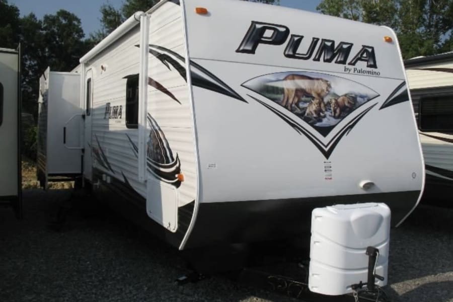 White Puma travel trailer RV rental, featuring a front graphic of a puma & cubs, with an extended slide-out for space.