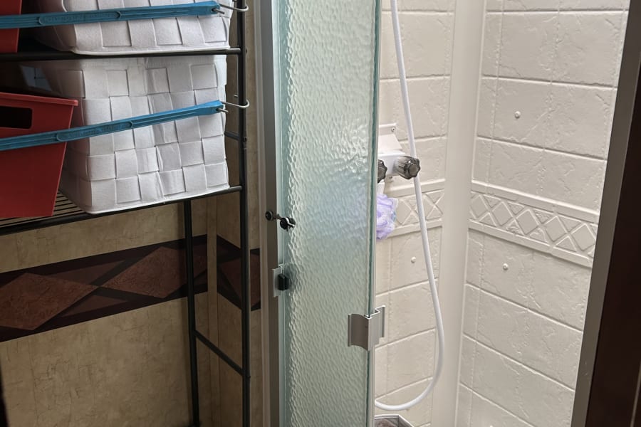 RV rental bathroom: compact design with a shower, toilet, and practical shelving with woven baskets for organized storage.