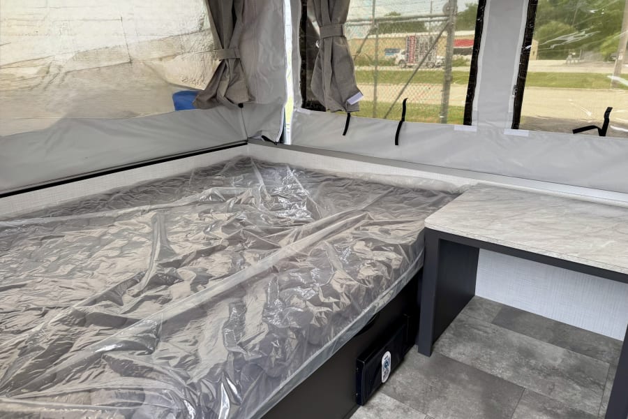 RV rental pop-up camper interior: plastic-covered mattress, small counter, and mesh windows. Ready for your trip!