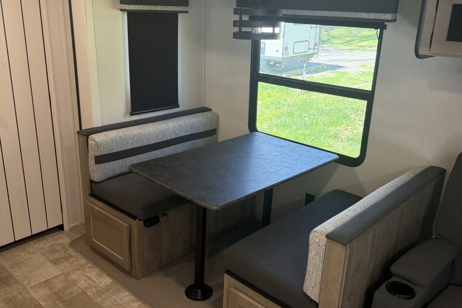 Modern RV rental dinette featuring stylish bench seating, a functional table, and bright window views for dining or relaxing.