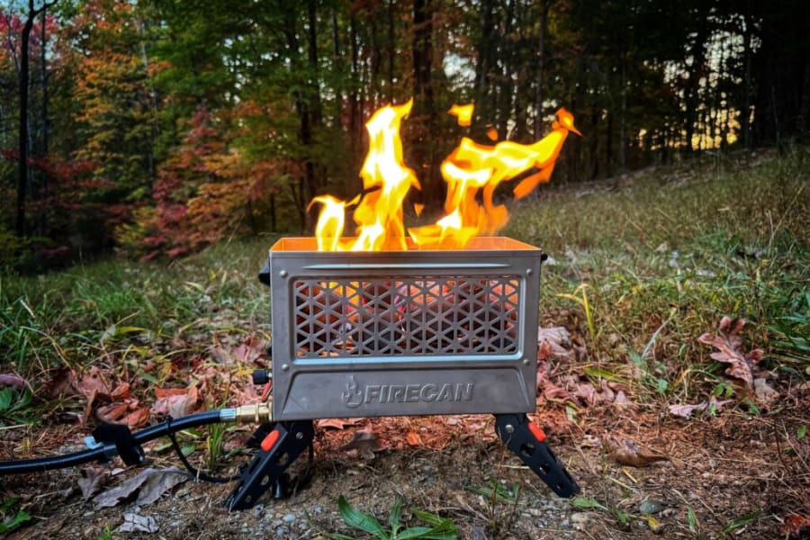 Warm up your RV rental trip with a portable FIRECAN gas fire pit, burning bright amidst autumn leaves.