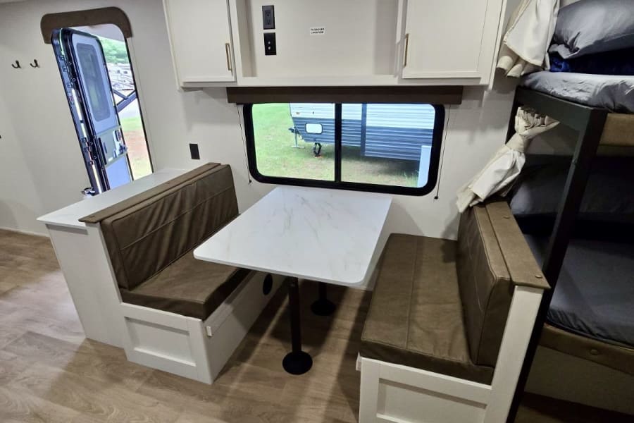 This RV rental features a practical dinette with bench seating, bunk beds, and an open entryway. Ideal for road trips.