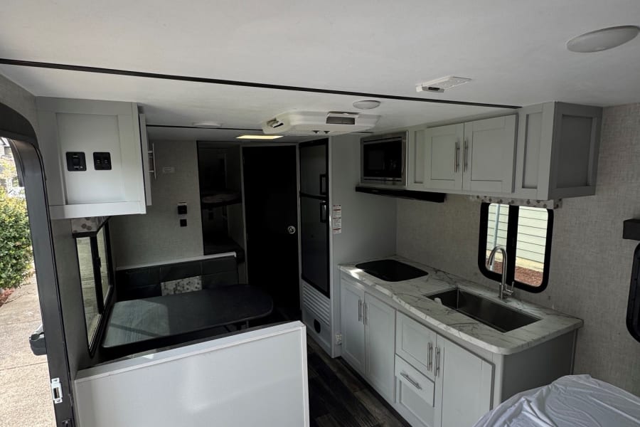 Spacious, modern RV rental interior featuring kitchen, dining, and sleeping areas, plus bunk beds for travel.