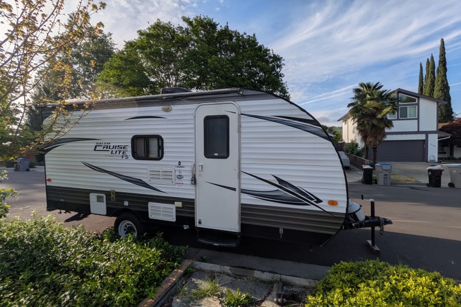 Salem Cruise Lite RV rental parked on a street near trees and a house, ready for your next adventure.