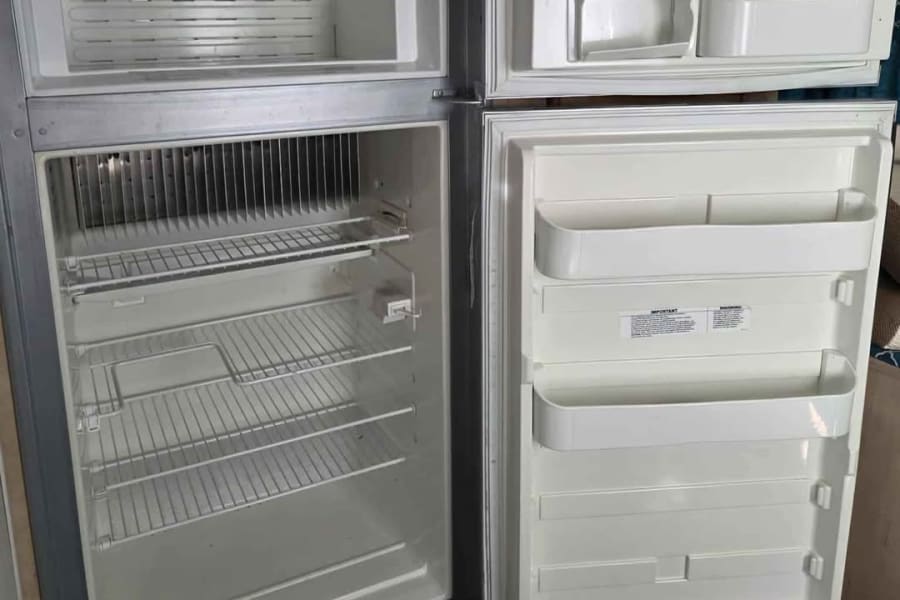 Clean RV rental refrigerator with open doors, showing empty shelves and door storage, ready for your next road trip.
