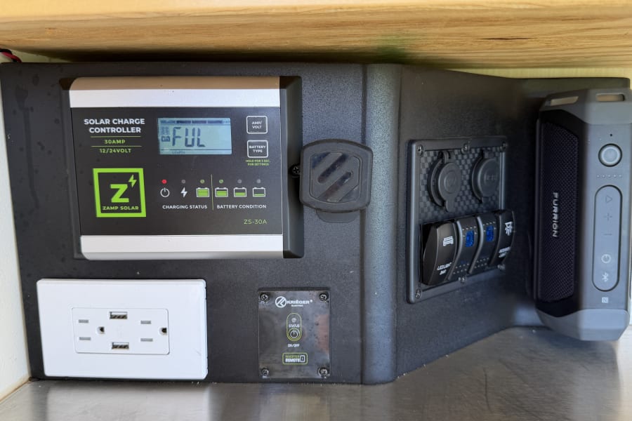 RV rental's power station: Zamp Solar controller (FUL charge, LiFePO4), outlets, inverter remote, and Furrion speaker for adventures.