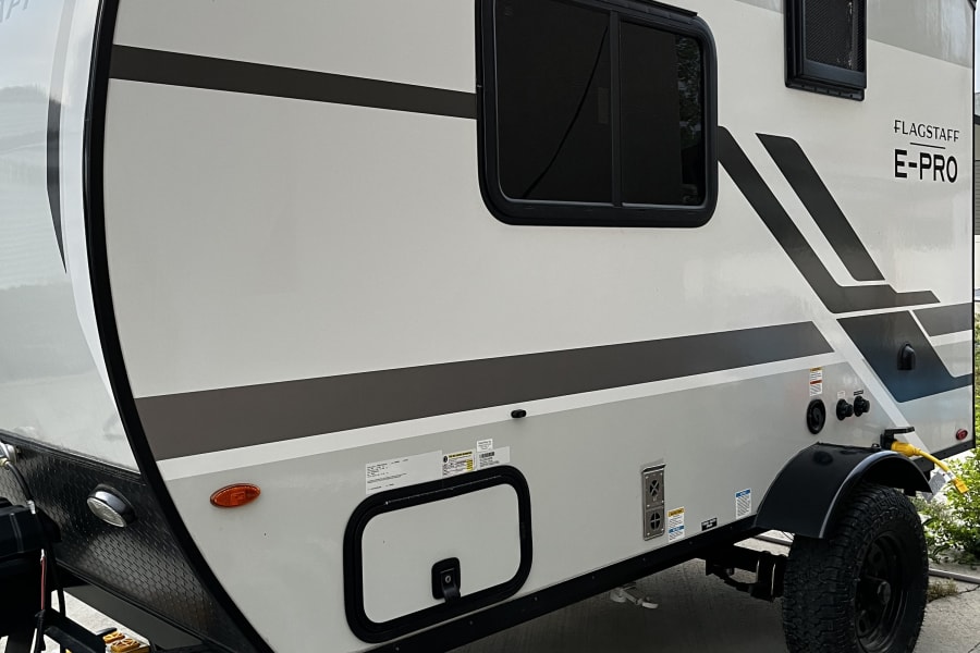 Flagstaff E-Pro travel trailer, a white and grey RV rental parked with stabilizers. Perfect for your outdoor adventure.