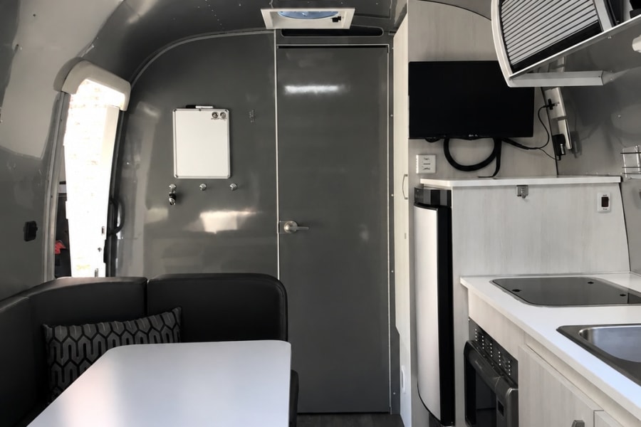 Modern rv rental interior featuring a bright kitchen, cozy dining booth, and sleek ceiling with AC. Ready for adventure!