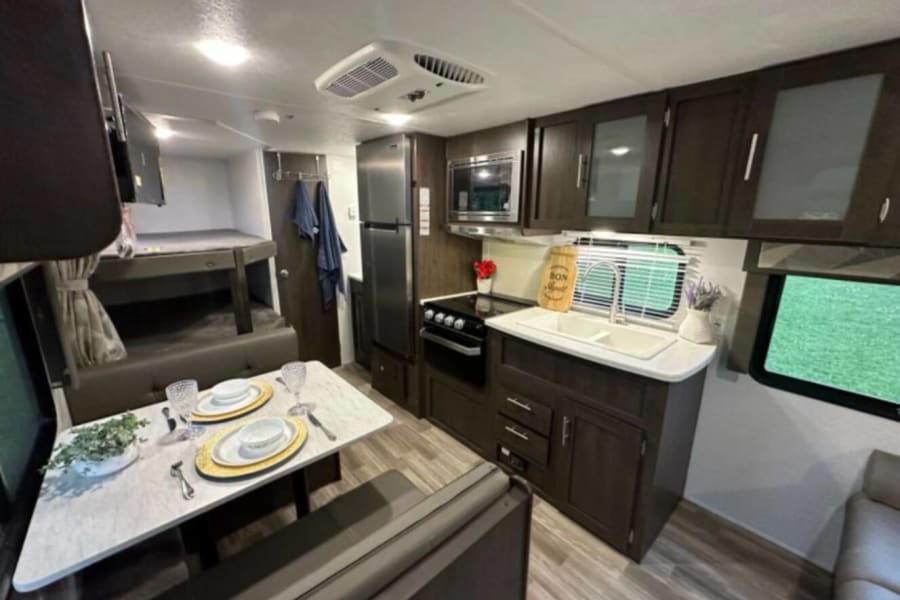 This RV rental offers a well-equipped kitchen, a comfortable dinette set for two, and cozy bunk beds.