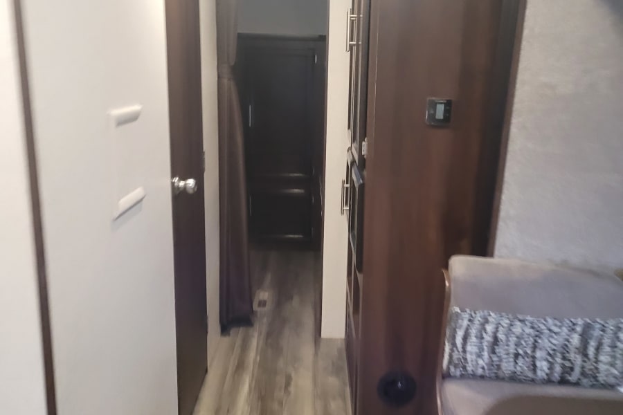 RV rental interior: A narrow hallway leading past storage, a dinette, and a door, showing compact modern living.