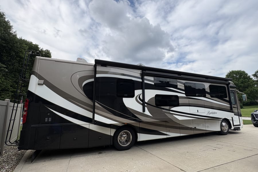 Stylish Berkshire RV rental with eye-catching black, white, and gray swirl graphics, parked on a driveway.