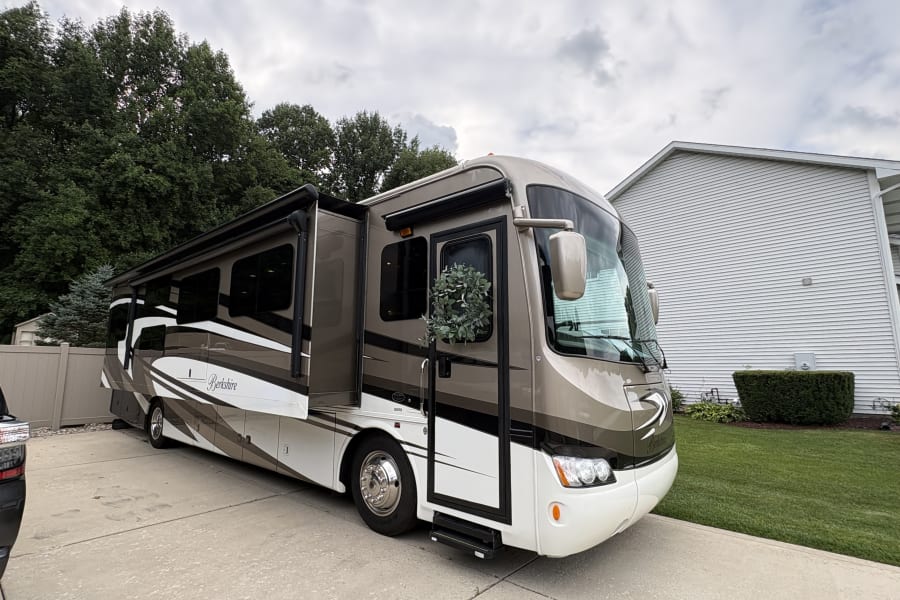 Elegant Berkshire RV for rv rental, parked with slide-outs open. Beige and white motorhome with a wreath, ready for your next travel adventure.