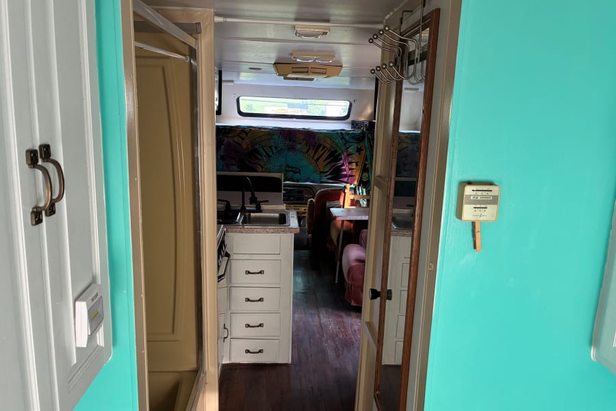 Cozy rv rental interior featuring a compact kitchen, dining area, and vibrant turquoise walls.