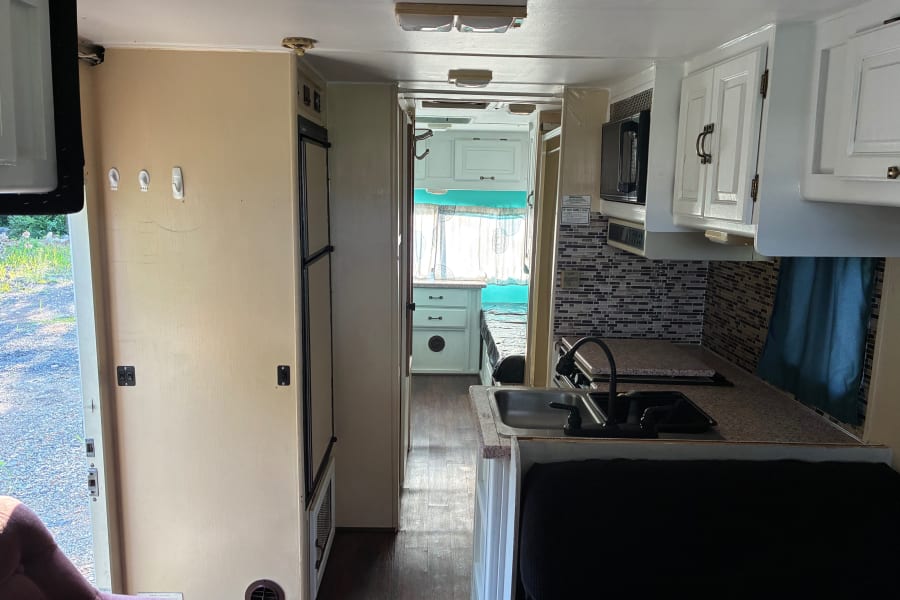 View inside an rv rental: functional kitchen, ample living space, and a cozy bedroom in the back.