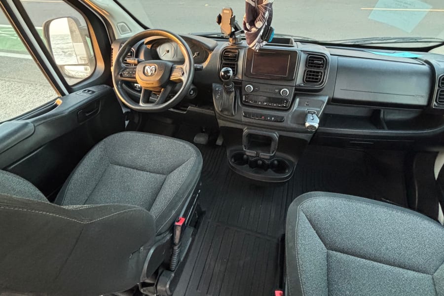 RV rental's clean van interior. Dashboard, steering wheel, seats, & mirror reflecting water. Ready for your adventure.