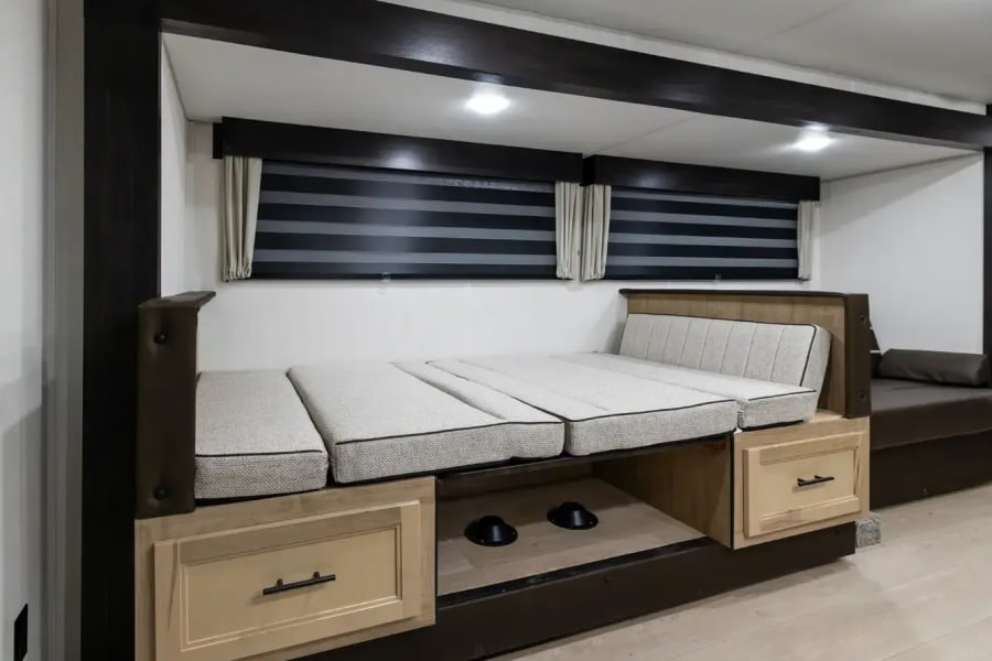 Experience comfort in this RV rental with a convertible dinette-to-bed setup, storage drawers, and sleek window blinds.