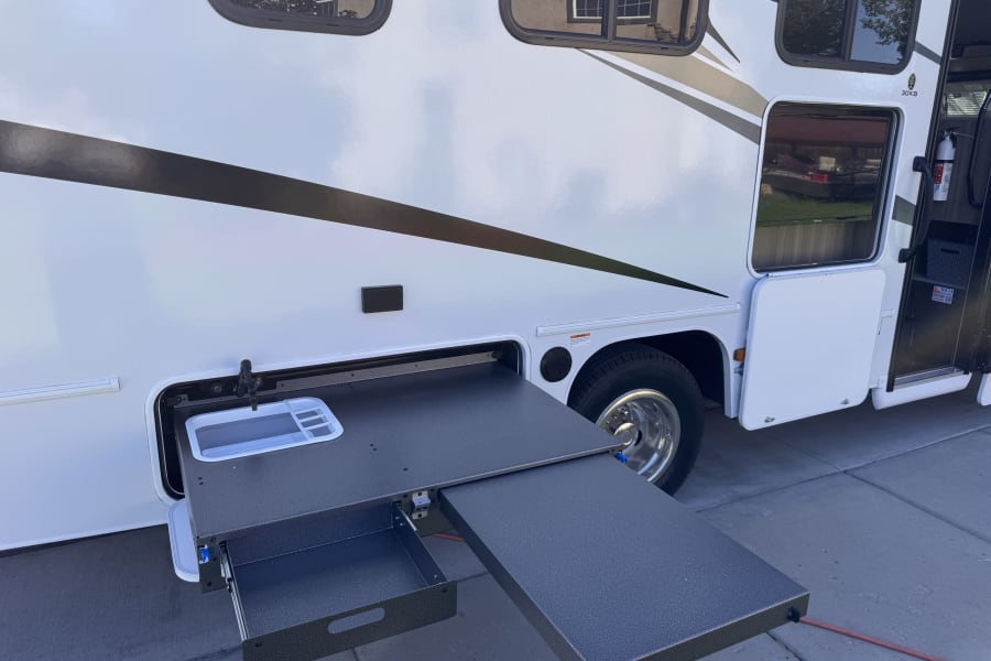 This RV rental features a convenient pull-out outdoor kitchen with a sink and counter, perfect for mobile cooking.