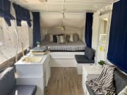 Updated pop-up camper RV rental interior features a cozy bed, compact kitchen, and comfortable seating areas.
