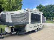 Grey pop-up RV rental (Jayco Jay Series) with AC, set up on a driveway for outdoor adventures.