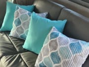 Stylish **RV rental** interior: dark couch with vibrant teal & patterned throw pillows. Ready for travel comfort!