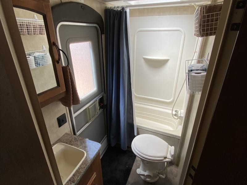 Full RV bathroom with tub/shower combo, sink, and toilet, with exterior door for easy access when out playing.