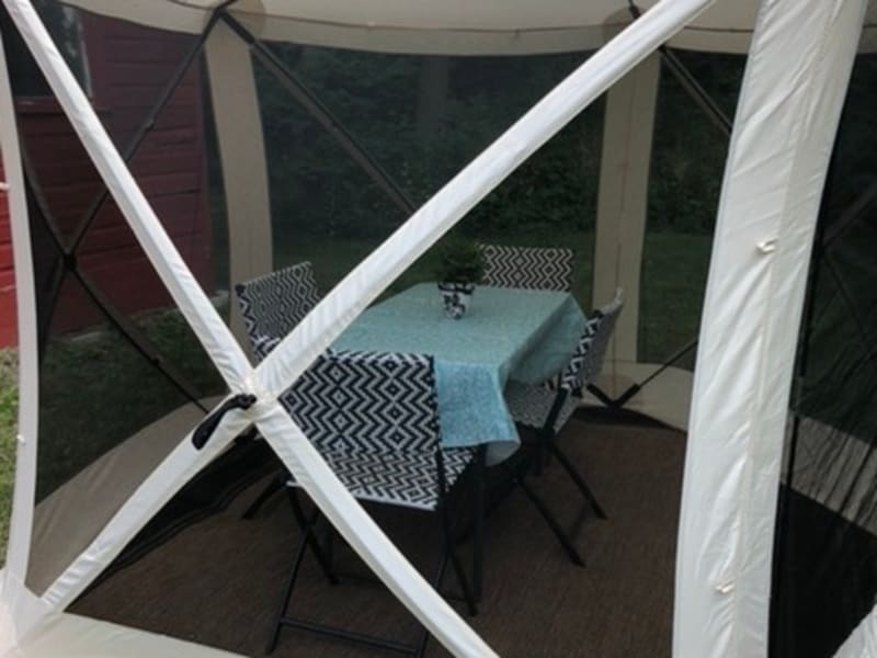 Screened in tent with tables and chairs in place of awning.