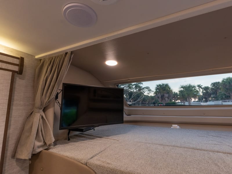 Bed over driver seat with pull down shade. and TV.