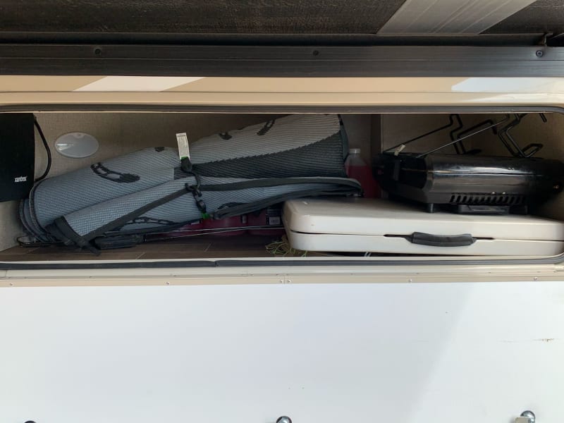 This compartment is 55w 17h 30d on the driver's side. It is where I store an outdoor rug, a small table, and hotdog forks with plenty of extra space.