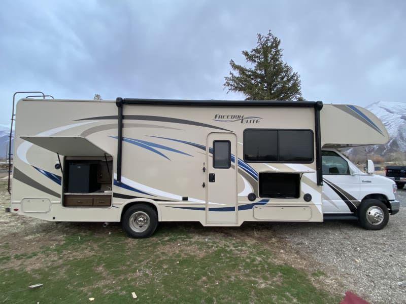 Passenger side exterior with outdoor TV, kitchen and RV entrance. 