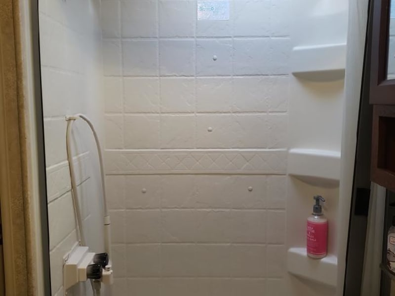 Roomy shower with hand held wand for convenience 