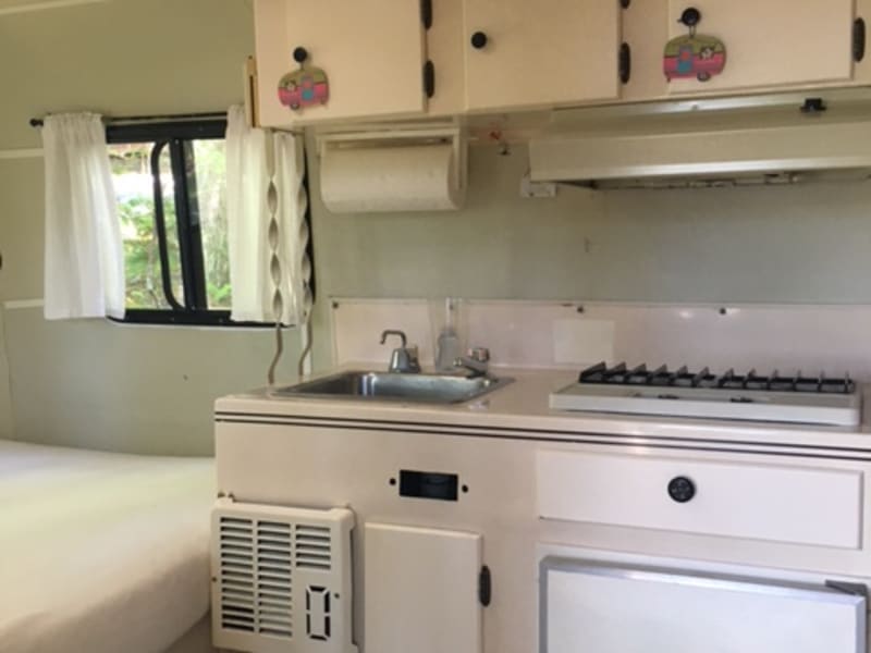 Kitchen with sink, cooktop, icebox.  Cabinets stocked with plates, bowls, cups, coffee mugs, pots, pans and toaster.  Cooking & eating utensils too!